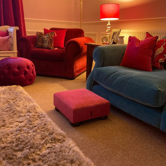 Fuchsia Pink Footstool wth dark wood feet in a lounge with a teal sofa and pink accessories