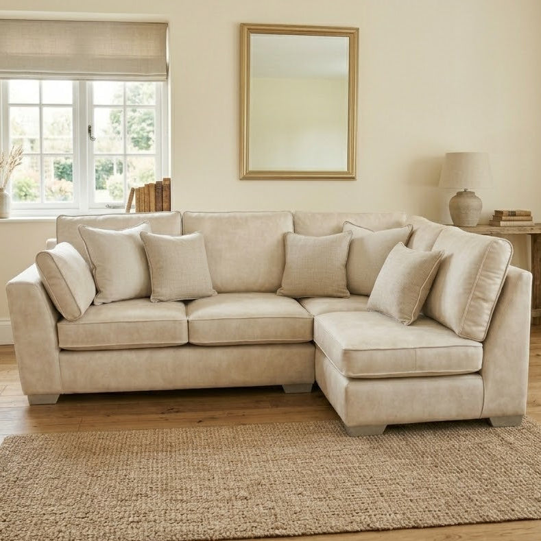 Beige sectional sofa in a living room with a mirror, lamp, and decor items.