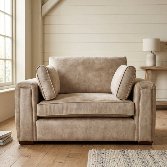 Beige armchair in a room with wooden flooring and a lamp in the background