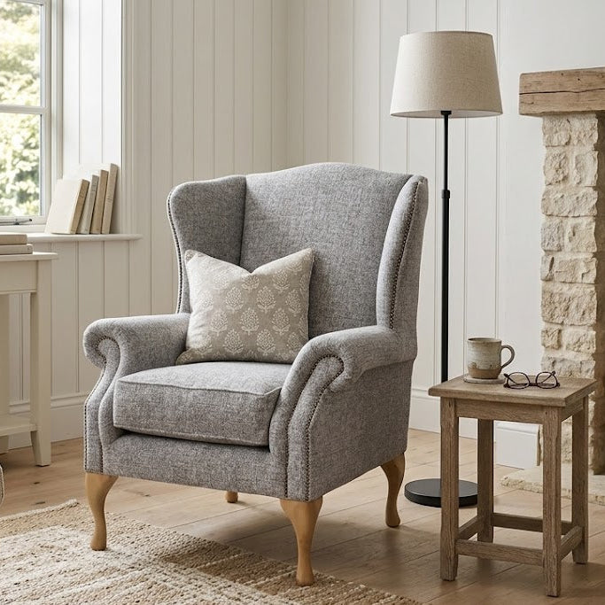 Cozy living room with a gray armchair, side table, and fireplace.