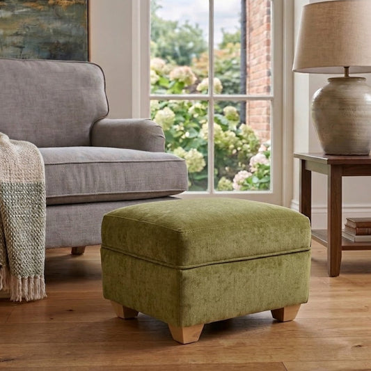 Living room with gray sofa, green ottoman, and lamp near a window.