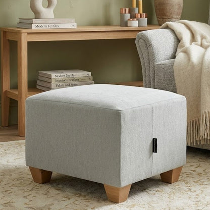 Living room with gray ottoman, sofa, side table, and decorative items.