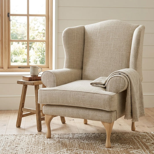 Beige armchair with a blanket in a cozy room with a window and wooden stool.