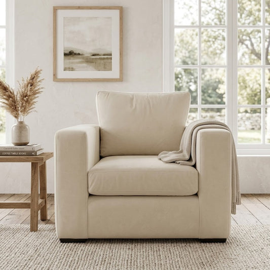 Beige armchair in a living room with a window and framed picture in the background