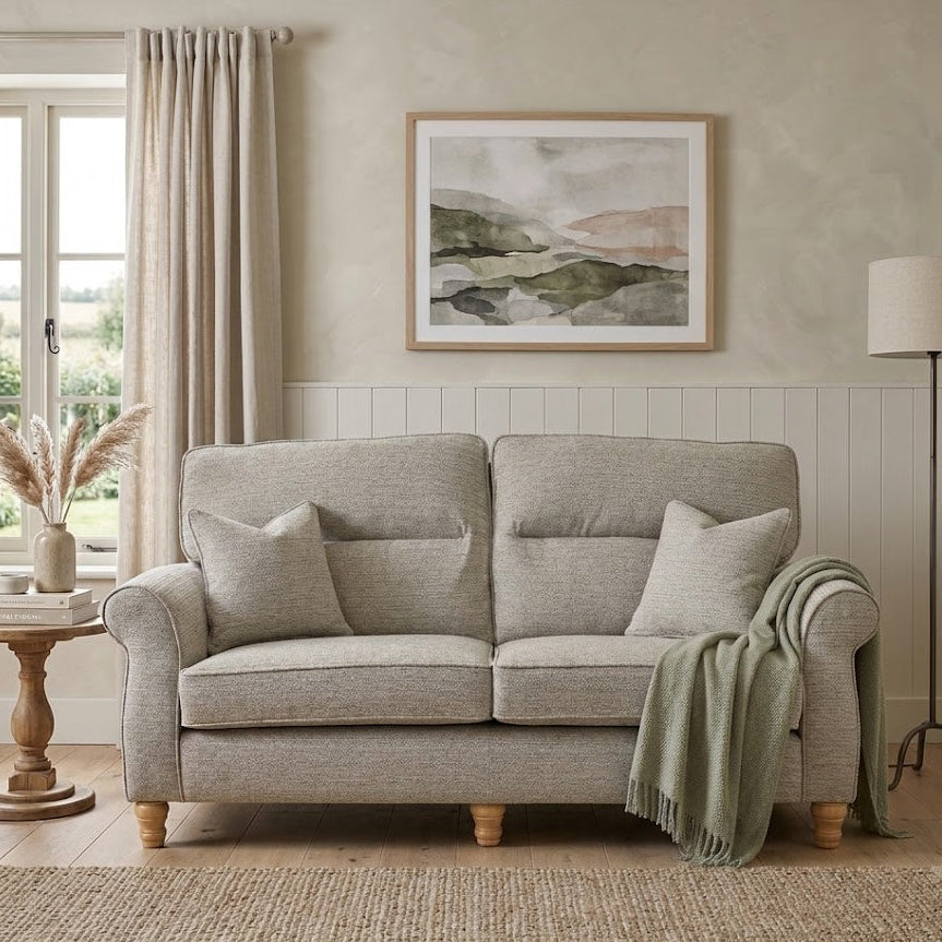 Gray sofa in a living room with a painting on the wall and a lamp.