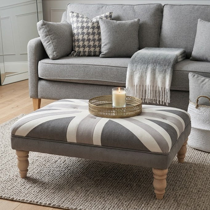 Gray sofa with striped ottoman and decorative items in a living room setting.