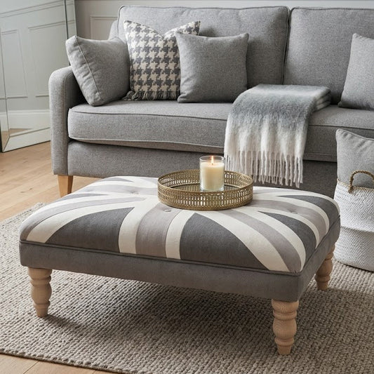 Gray sofa with striped ottoman and decorative items in a living room setting.