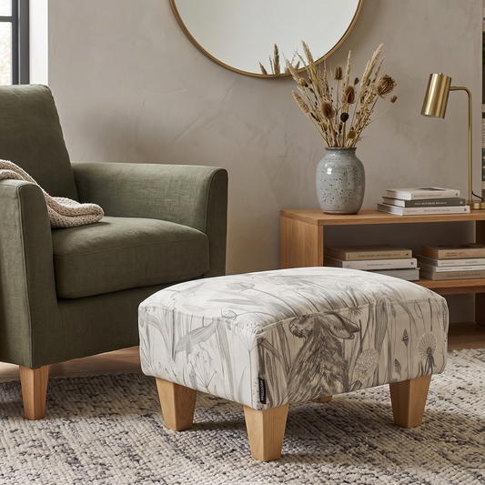Living room with a green armchair, patterned ottoman, and wooden side table.