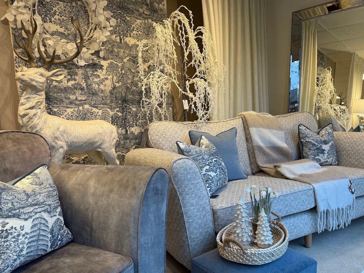Living room with gray sofa, decorative pillows, and wall art of deer and trees.
