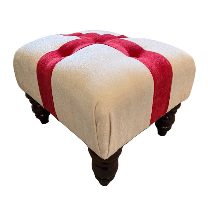 Beige ottoman with red and white striped pattern in front of a beige sofa.