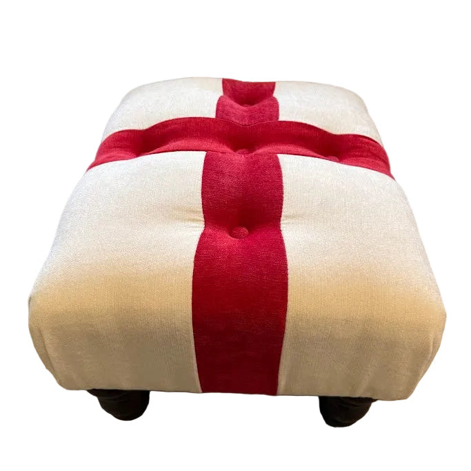 Beige ottoman with a red stripe in front of a beige sofa.