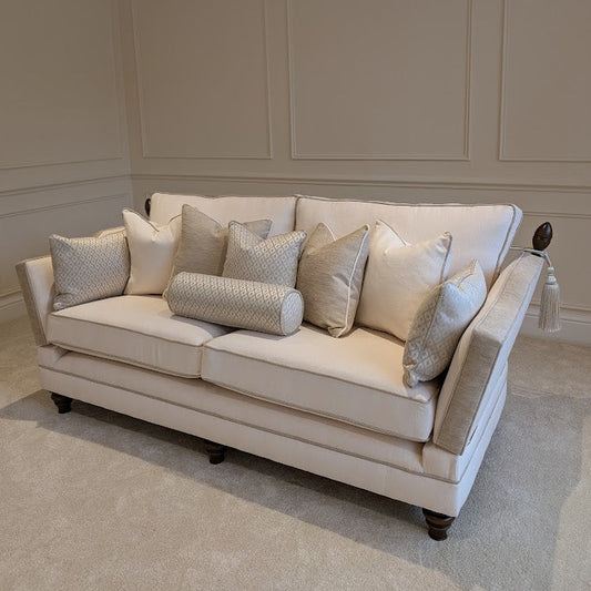 Beige sofa with decorative pillows in a room with panelled walls.