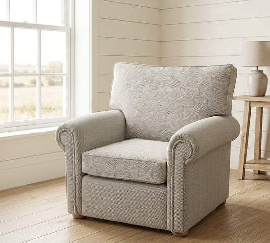 Beige armchair in a room with wooden flooring and a lamp on a side table.