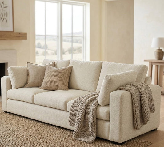 Beige sofa in a living room with a fireplace and large window.