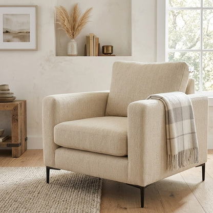 Beige armchair with a plaid blanket in a living room setting.