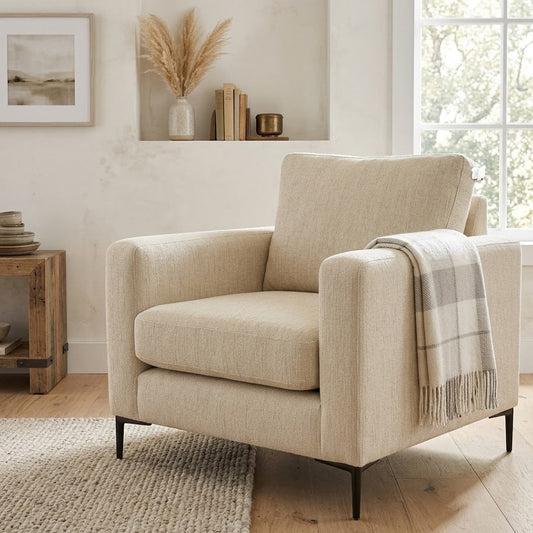 Beige armchair with a plaid blanket in a living room setting.