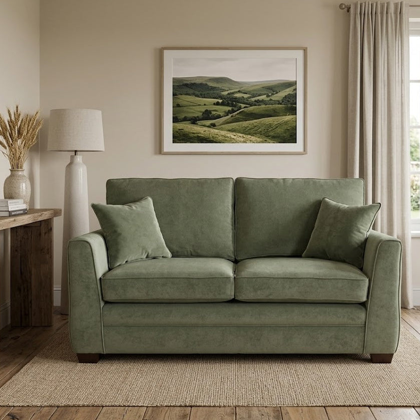 Green sofa in a living room with a painting of green hills on the wall.