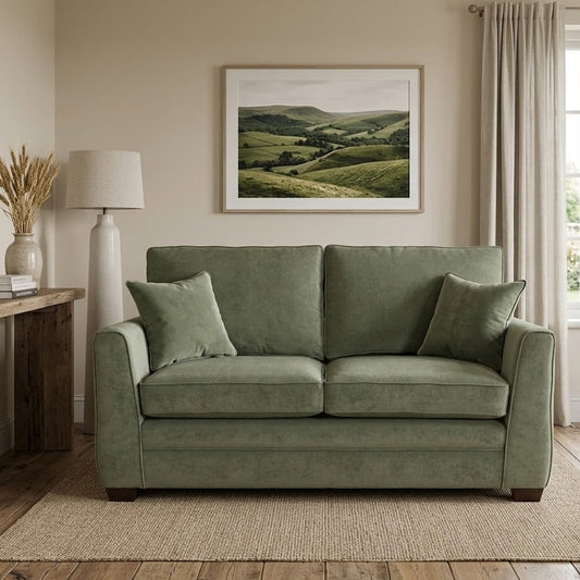 Green sofa in a living room with a painting of green hills on the wall.