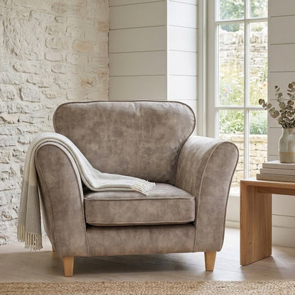 Brown armchair in a room with a stone wall and large window.