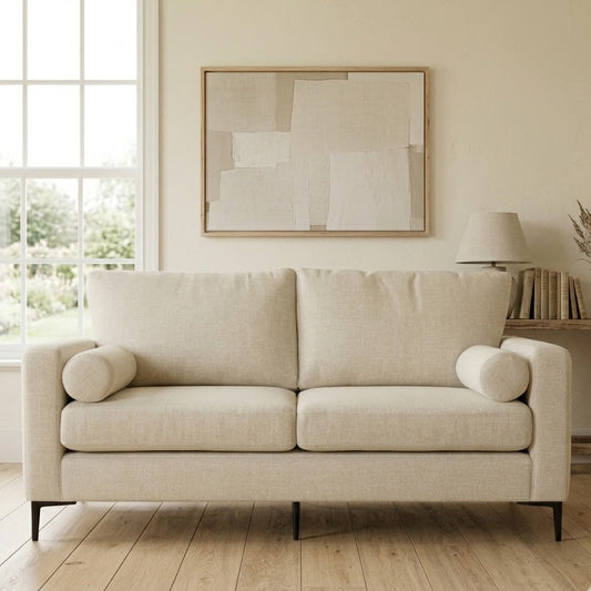 Beige sofa in a living room with a window and wall art.