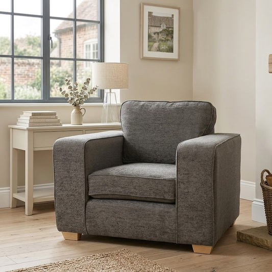 Gray armchair in a living room with a side table and window in the background