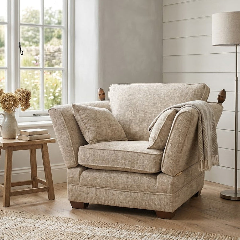 Beige armchair in a room with a window, lamp, and small table.