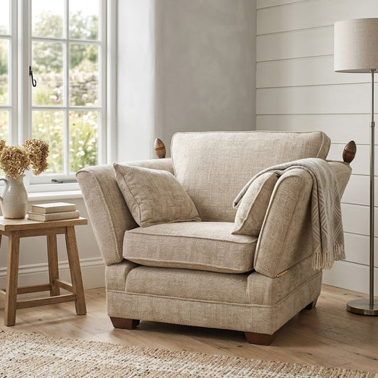 Beige armchair in a room with a window, lamp, and small table.