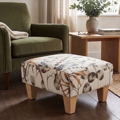 Green armchair with a patterned ottoman in a living room setting.