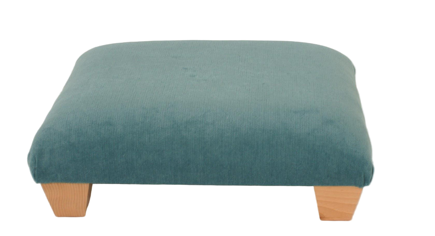 Teal ottoman with wooden legs on a plain background